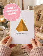 A person holds a white greeting card with a yellow tent illustration and the text 'YOU'RE TENT-SATIONAL' in a cozy indoor setting. A pink scalloped badge in the top left says 'Add a message inside'.